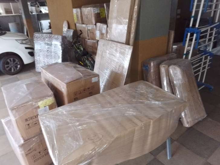 Household goods packed, shrink-wrapped and staged at Chennai apartment stilt parking before transit to Vijayawada