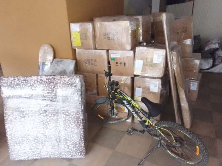 Cartons, wrapped items and a bicycle in an indoor space