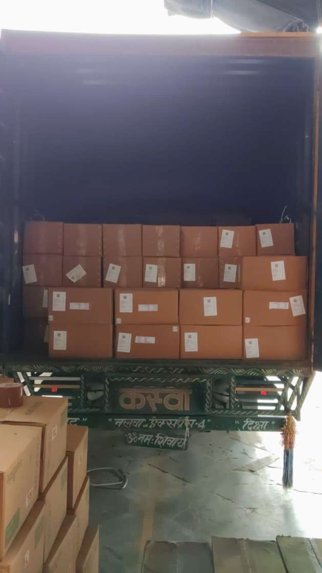 Cartons stacked at the rear of a truck, with more cartons beside it.